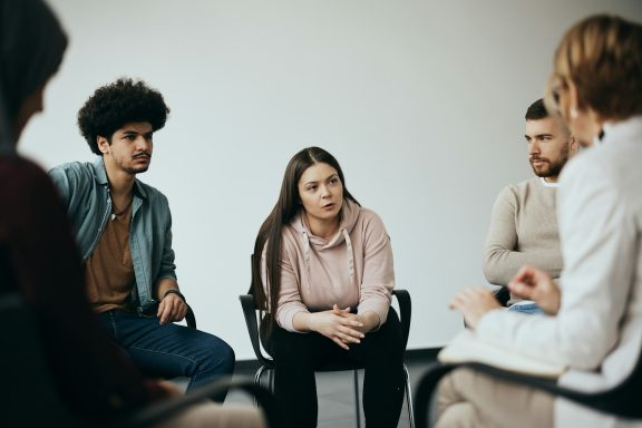 Eine Gruppe von fünf Personen in einer Diskussion, entspannt sitzend im Stuhlkreis.